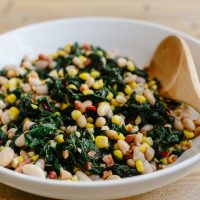 Swiss chard with pancetta, corn and beans in white bowl