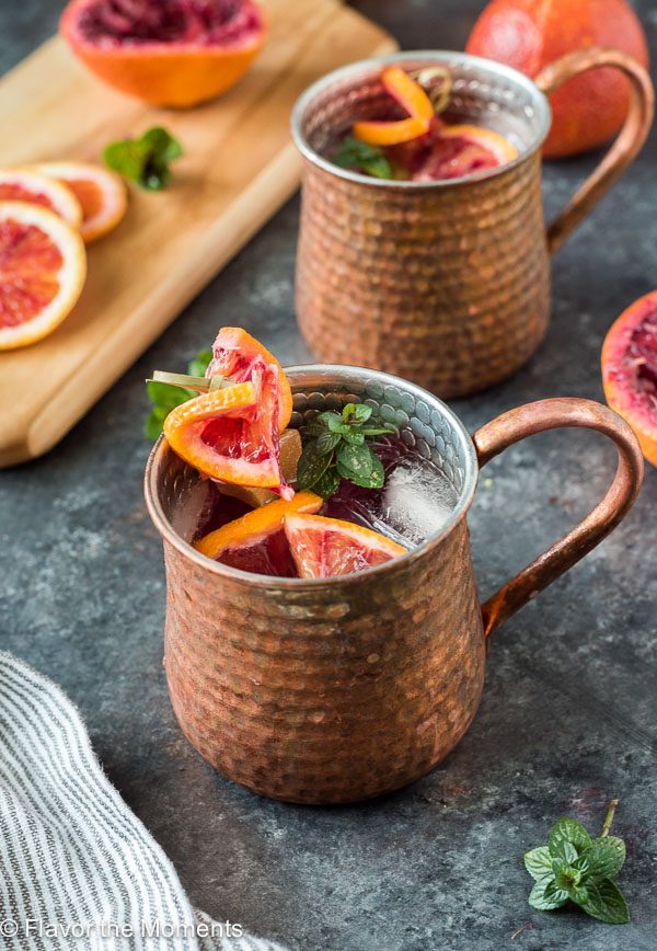 Blood orange mule in copper mug with blood oranges and mint