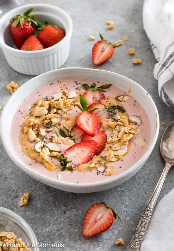 Strawberry smoothie bowl in white bowl with granola and fruit on top