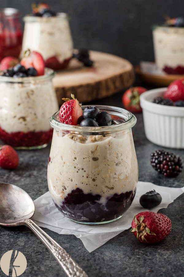 Chia jam overnight oats in jars with berries on top