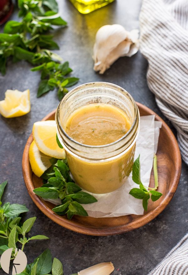 Greek dressing in mason jar with oregano and lemon