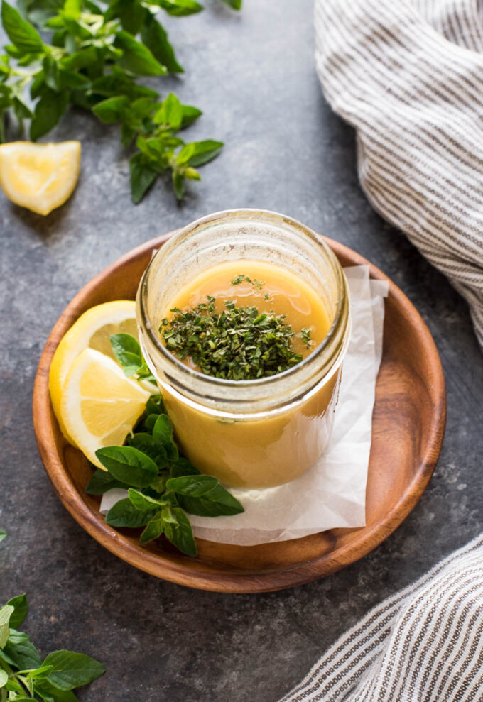 Greek dressing in jar with fresh oregano on top.