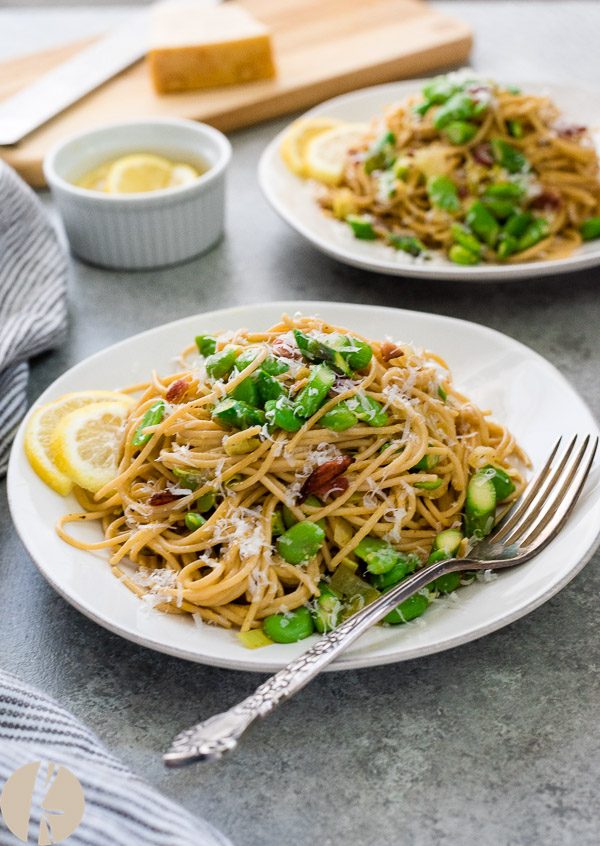 Spring spaghetti carbonara on a plate with bacon and fava beans