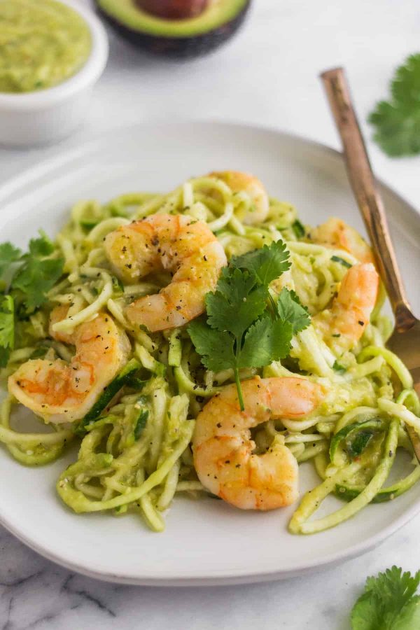 Tomatillo salsa shrimp zoodles on a white plate with a fork.