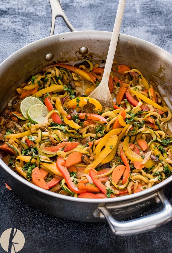 Vegetarian thai peanut zucchini noodles in a skillet with wooden spoon