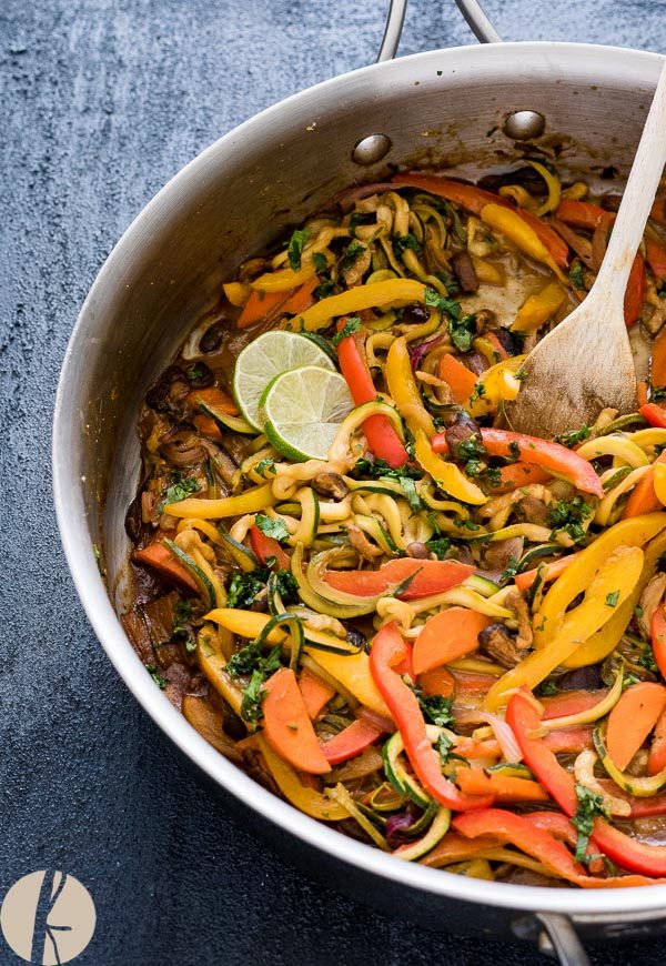 Vegetarian thai peanut zucchini noodles in a skillet with wooden spoon