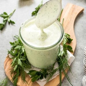Greek yogurt ranch drizzling off of spoon into a jar