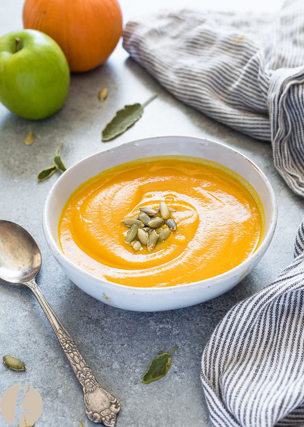 Bowl of roasted pumpkin apple soup topped with pepitas