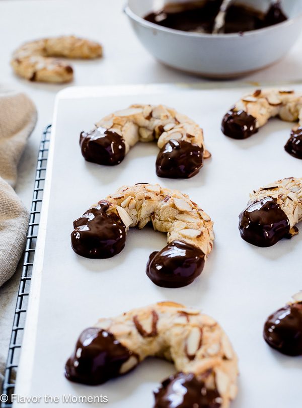 Chocolate dipped almond horn cookies on baking sheet