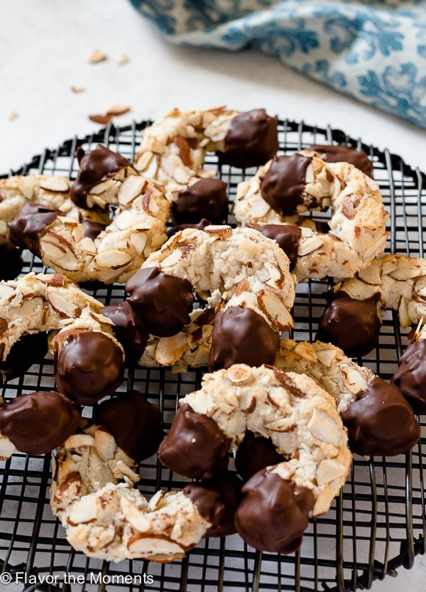 Chocolate dipped almond horn cookies piled on wire rack