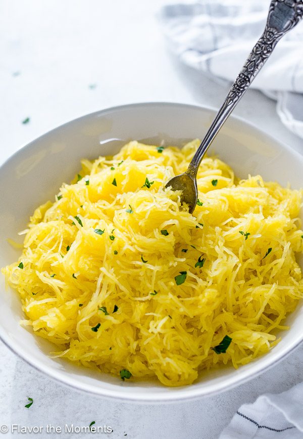 Bowl of spaghetti squash with parsley on top and fork buried into the middle