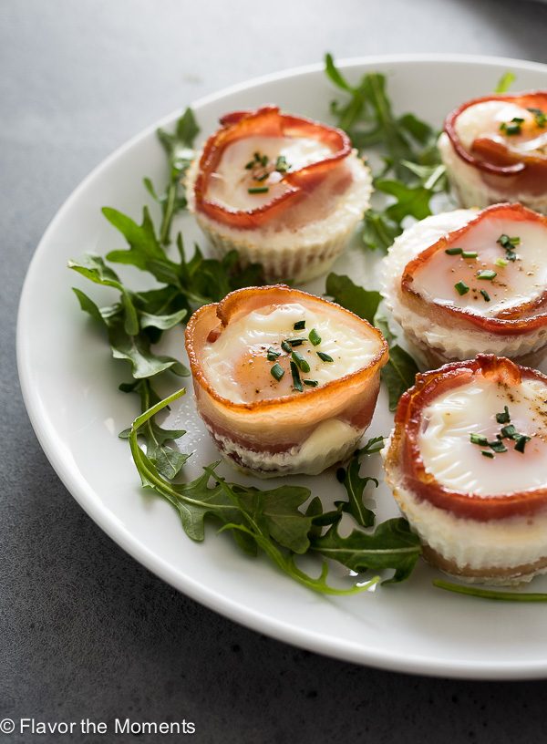 Bacon egg cups on a white plate with arugula