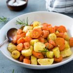 Roasted carrots and parsnips in a white bowl with spoon