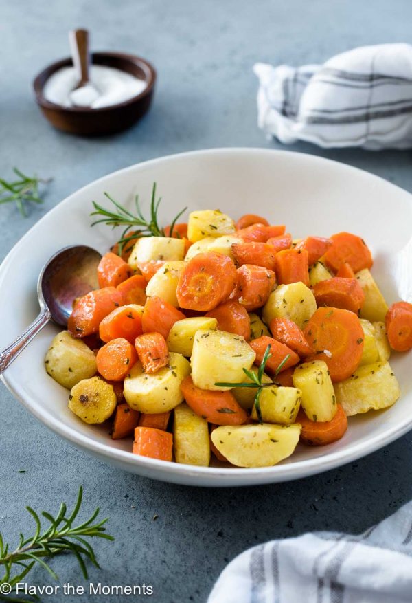carrots and parsnips in a white bowl with a spoon