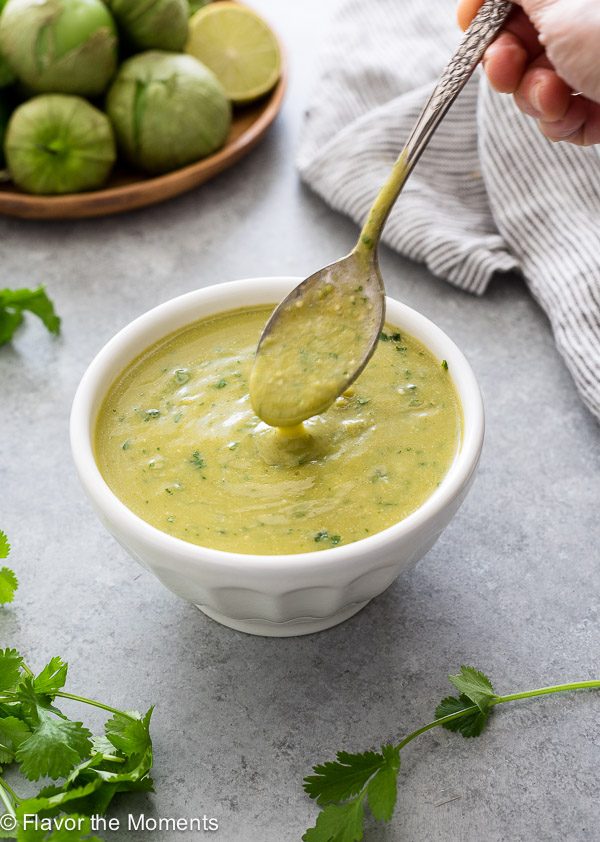 green enchilada sauce in bowl with spoon pouring
