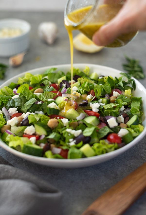 front view of dressing pouring onto Greek chopped salad