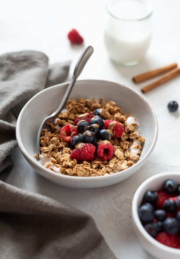 front shot of almond butter granola in bowl with berries and almond butter drizzle