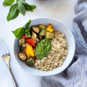 Roasted vegetable pesto quinoa bowl in bowl with basil