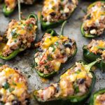 front view of stuffed poblano peppers on a sheet pan with melted cheese