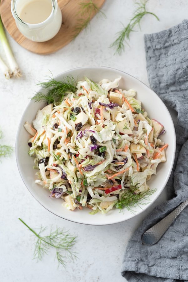 overhead shot of bowl of creamy no mayo coleslaw with gray linen