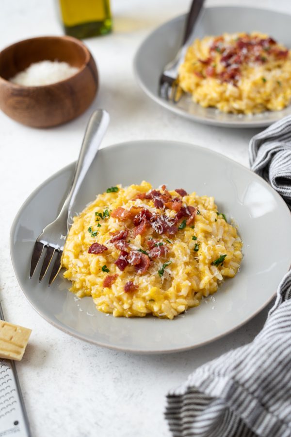 angled shot of pumpkin risotto instant pot on a plate with crumbled bacon