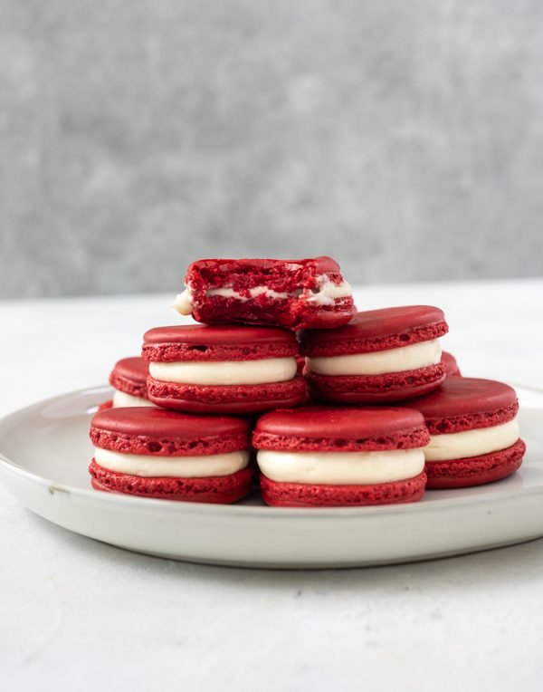 plate of red velvet macarons with a bite out of top cookie