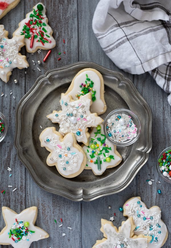 Overhead shot of Christmas sugar cookies on silver plate with sprinkles
