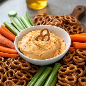 close up of pub cheese dip in a bowl with pretzel dipped in the center