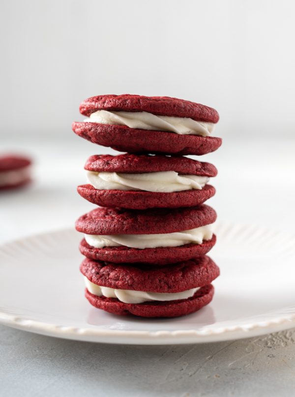 Stack of red velvet sandwich cookies on a white plate