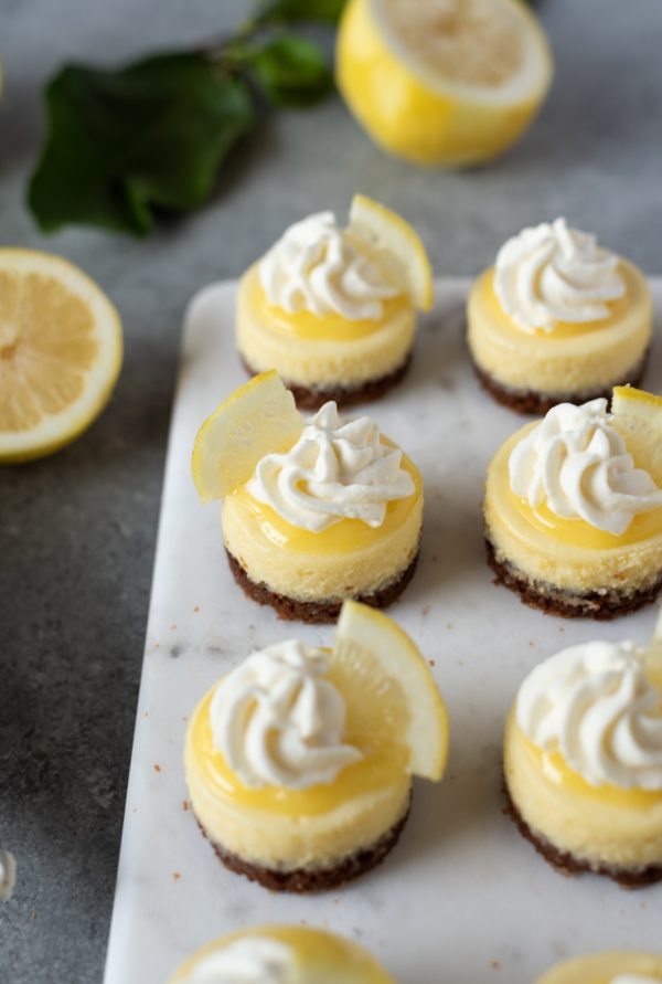 close up of mini lemon cheesecakes topped with lemon curd and whipped cream