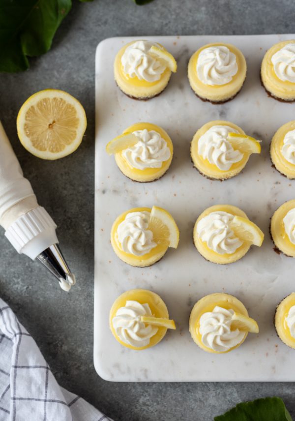 overhead shot of mini lemon cheesecakes topped with whipped cream and lemon slice