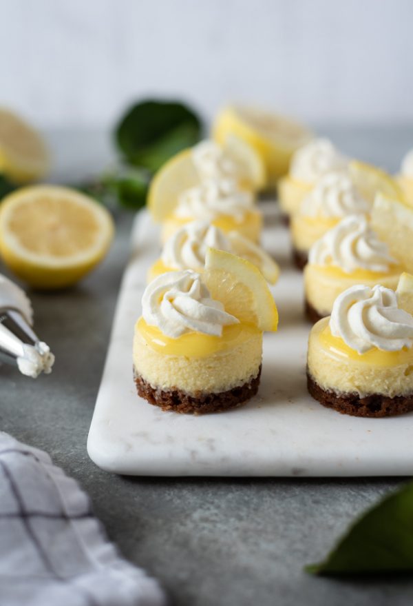 close up front shot of mini lemon cheesecakes on marble serving board