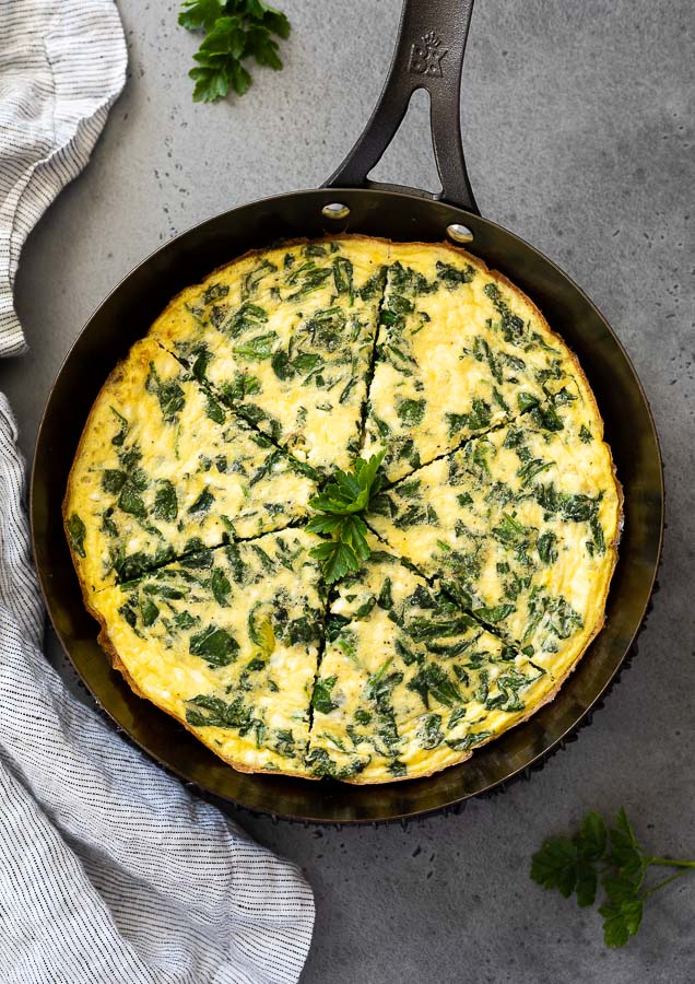 Spinach frittata in a skillet cut into slices
