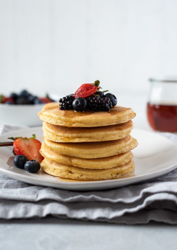 stack of grain free pancakes on a plate topped with berries