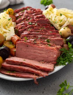 angled front shot of sliced corned beef and cabbage on a white serving platter