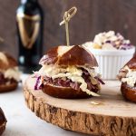 Guinness corned beef sliders with wooden pick through top.