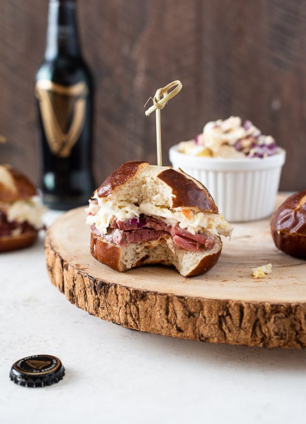 Guinness corned beef sliders on serving platter with a bite out of front slider