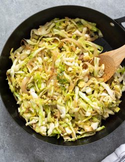 sautéed cabbage in skillet with wooden spoon