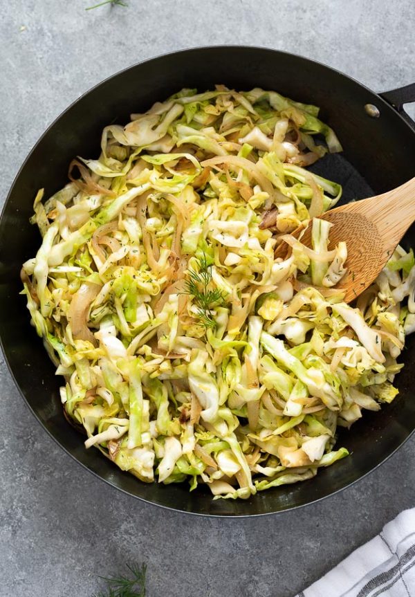 sautéed cabbage in skillet with wooden spoon
