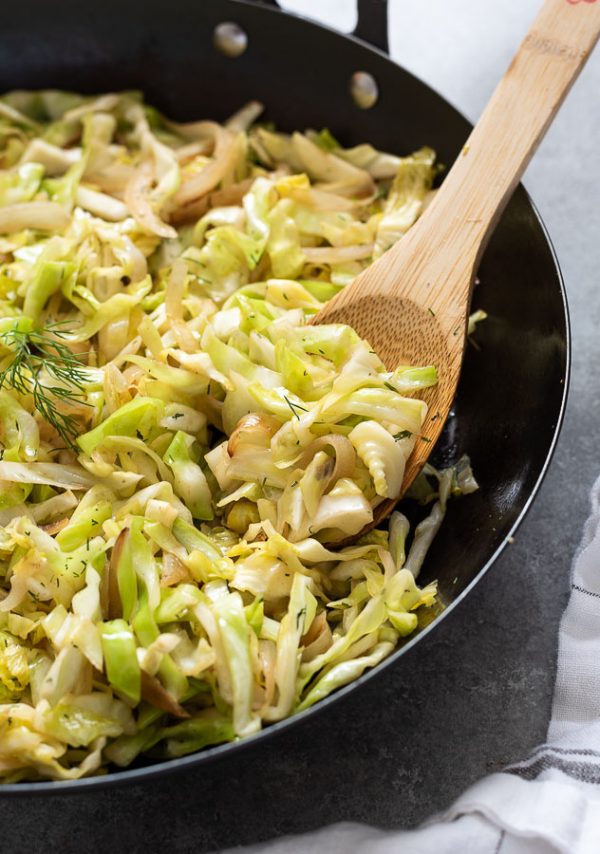 close up of wooden spoon with sautéed cabbage