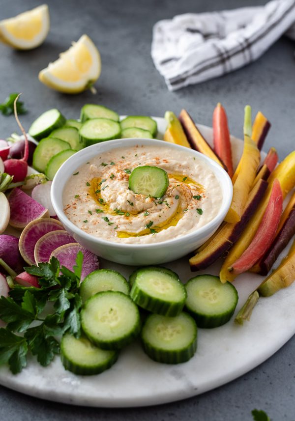 white bean hummus on a serving platter surrounded by fresh vegetables