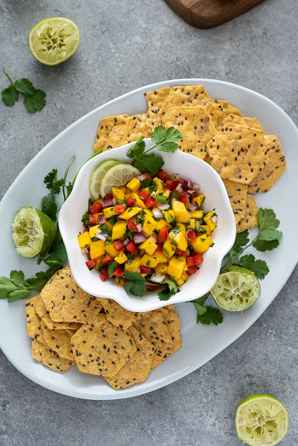 overhead shot of platter with mango salsa, chips and lime