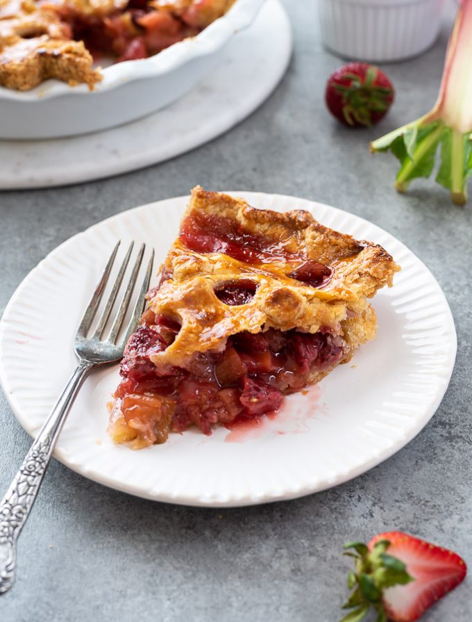 slice of strawberry rhubarb pie on a plate with fork alongside