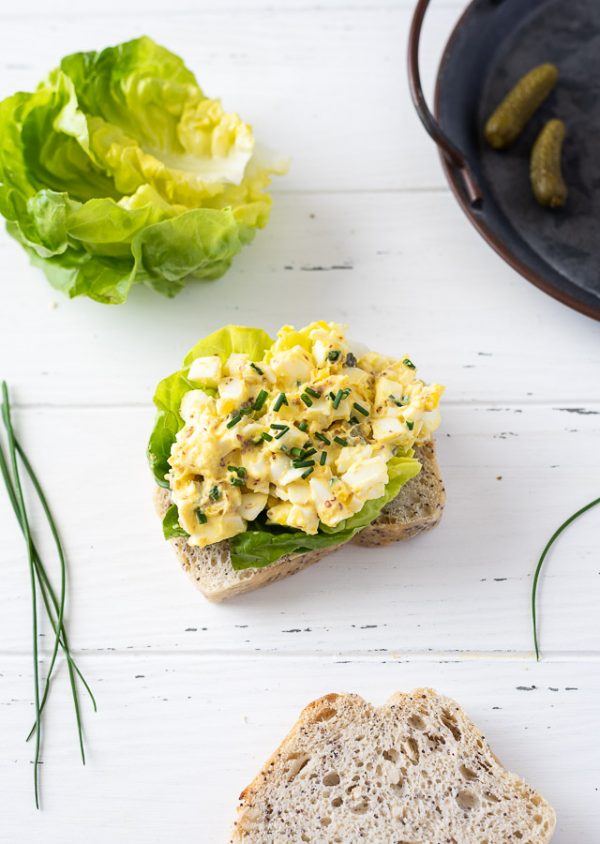 open faced egg salad sandwich with chives on top