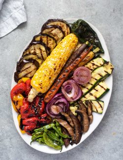 Grilled vegetables arranged on a white serving platter