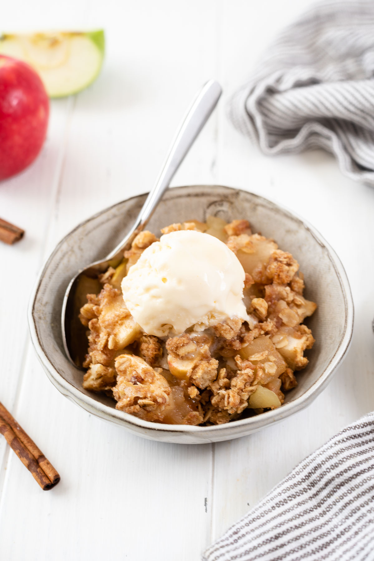 Serving of apple crisp in a bowl with ice cream on top