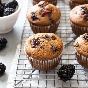 Blackberry muffins on wire rack with fresh blackberries