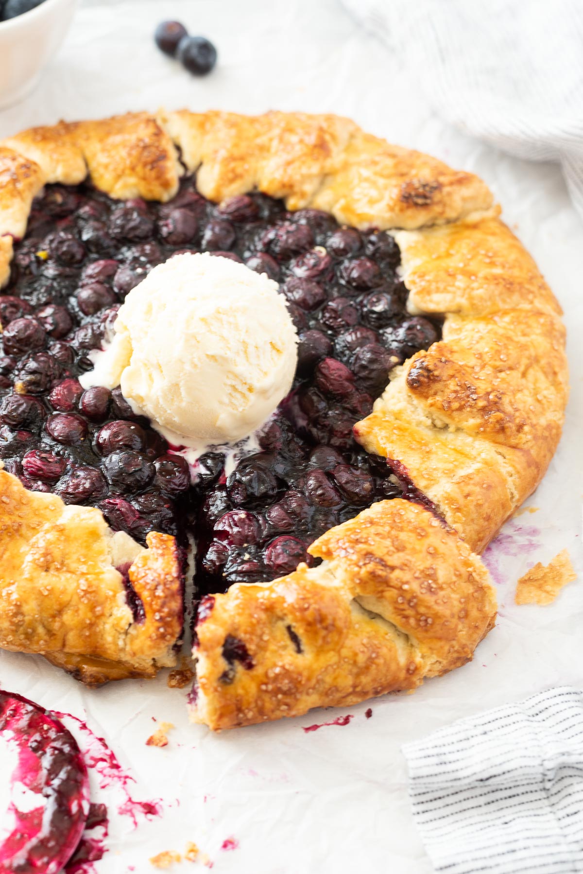 Blueberry galette with slice cut and ice cream in center