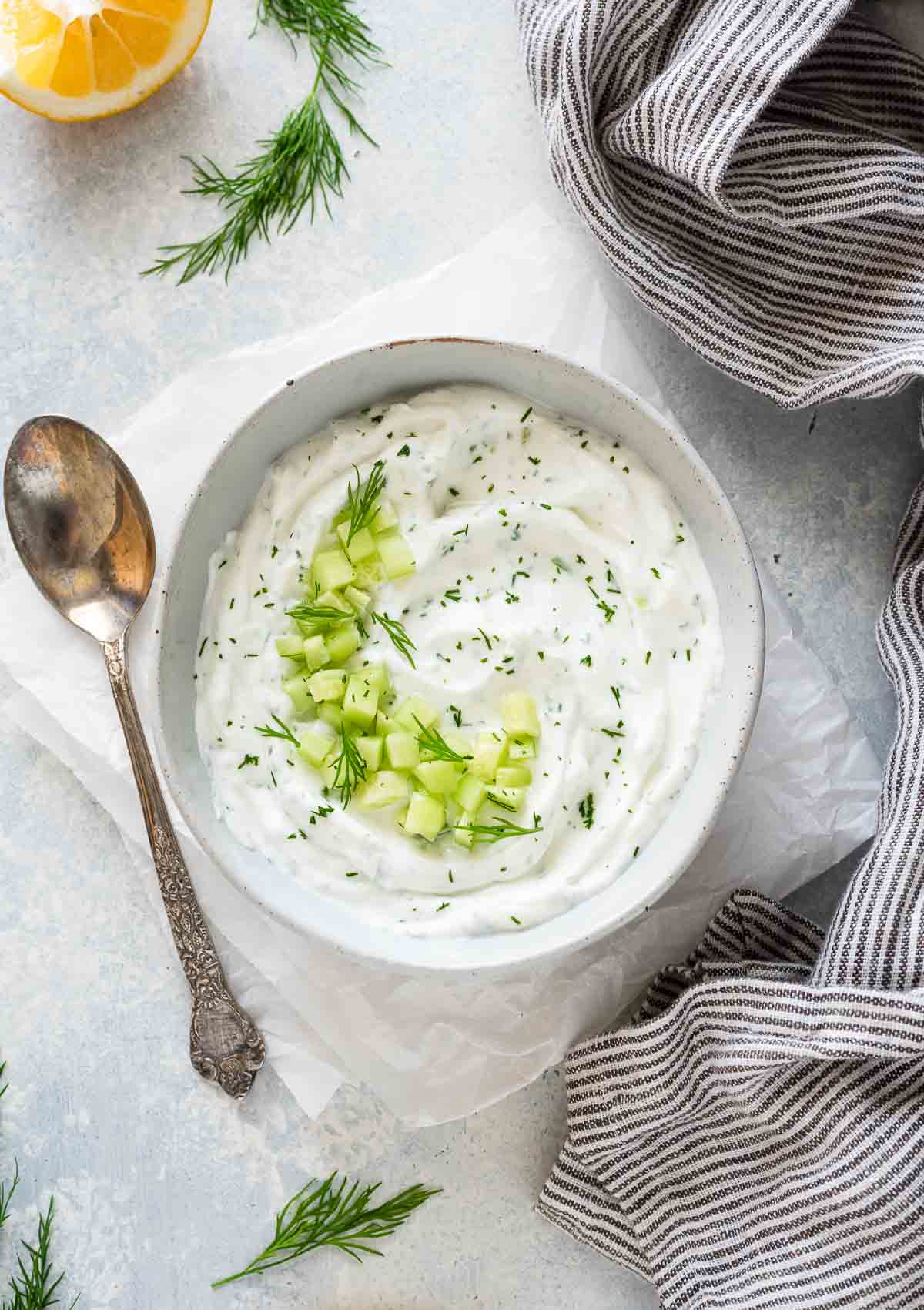 Greek tzatziki in white bowl with cucumber and dill on top