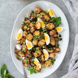 grilled potato salad on serving plate with fresh basil